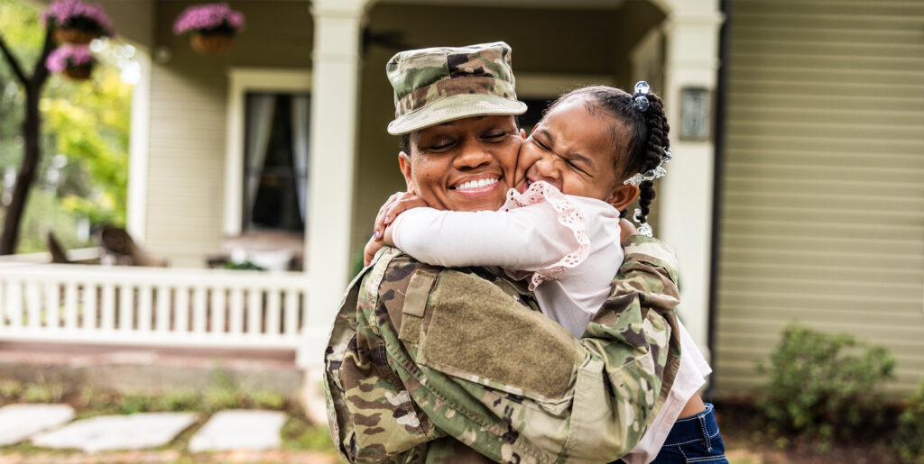 Female military service member hugging young girl and smiling