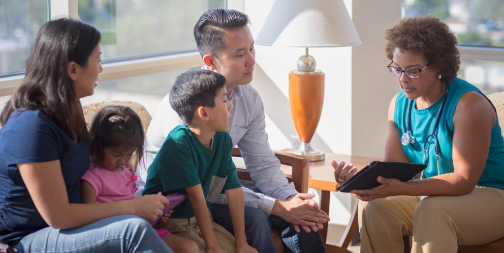 Family of four sitting on couch conversing with social worker